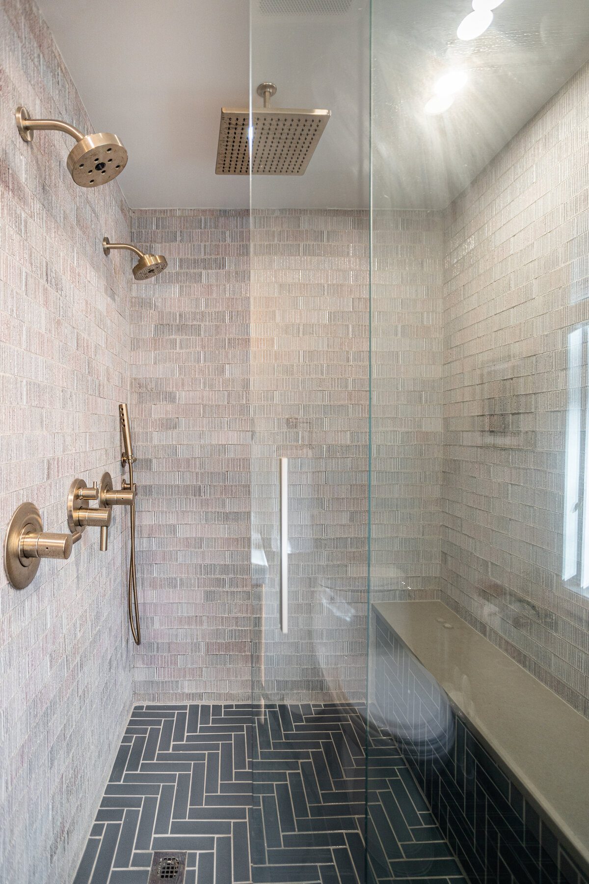 Modern bathroom with white tiled walls, a rainfall showerhead, and elegant fixtures.