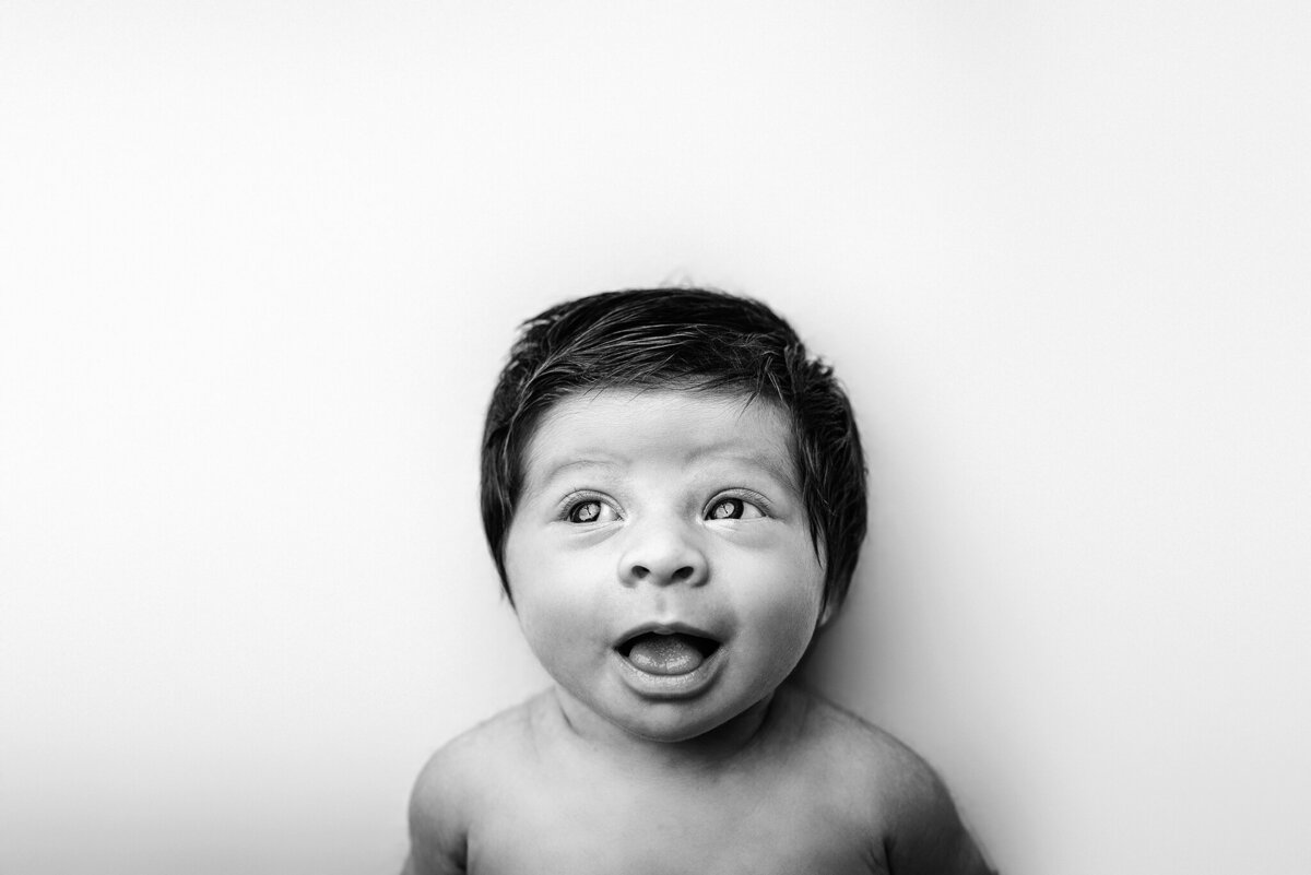 Black and white expression image of newborn girl with lots of hair in Atlantic Beach, FL.
