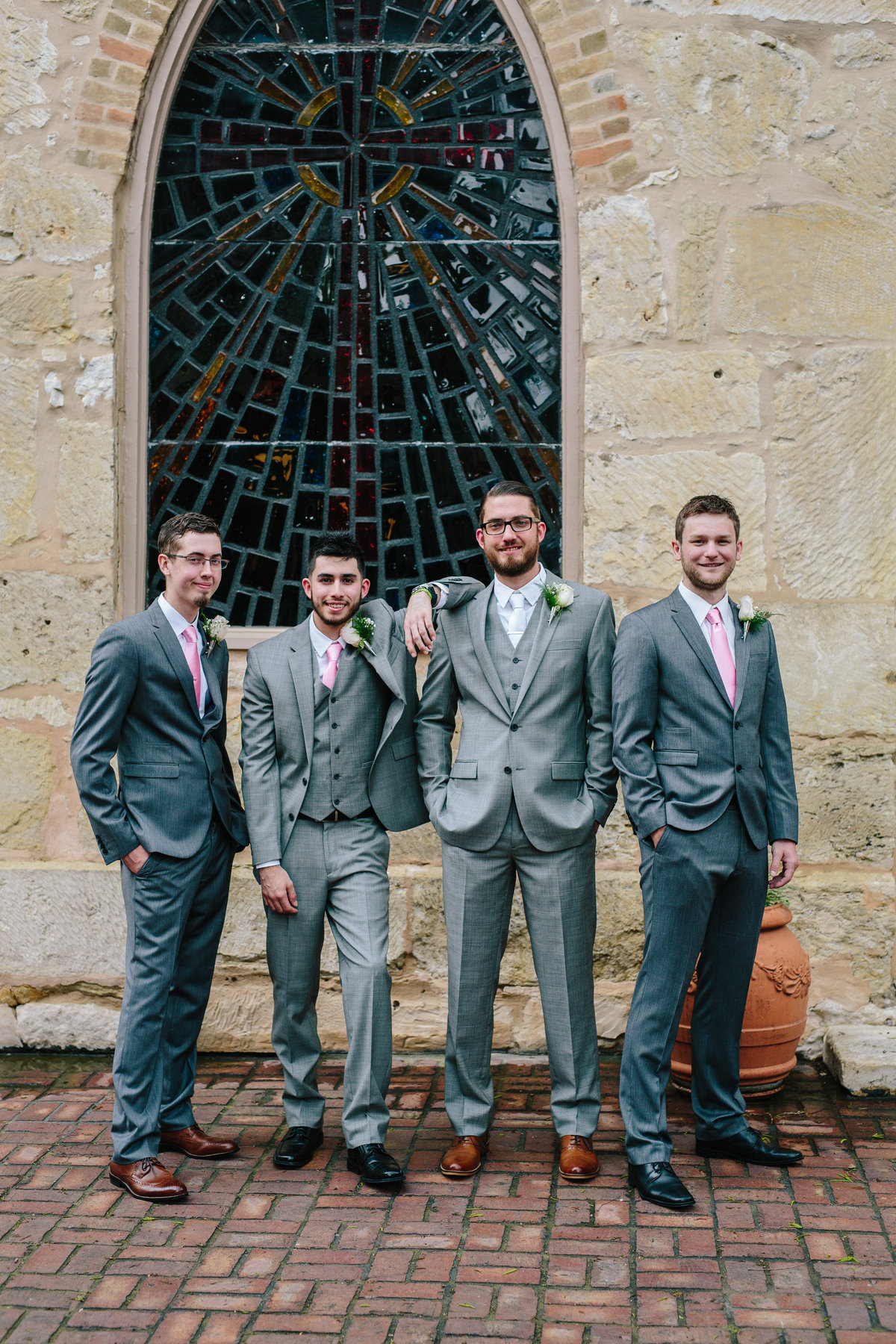 groom with groomsmen posing behind the Little Church of La Villita for a picture by San Antonio wedding photographer