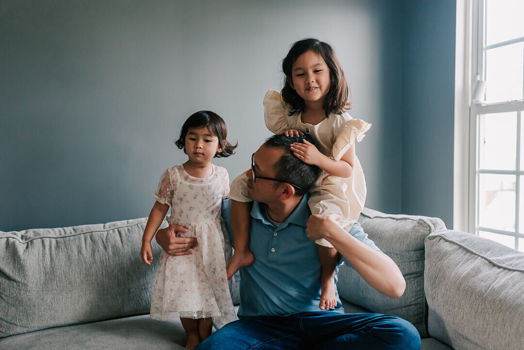 A dad enjoying a fun candid moment with his daughters during their newborn session