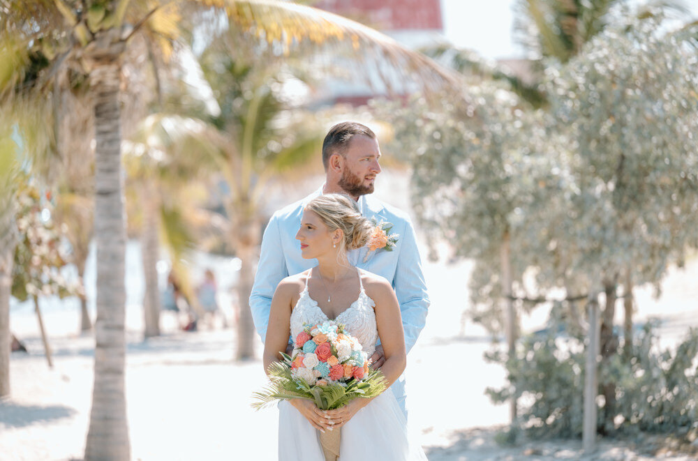 a bride and groom at their wedding in the Bahamas by palm  trees