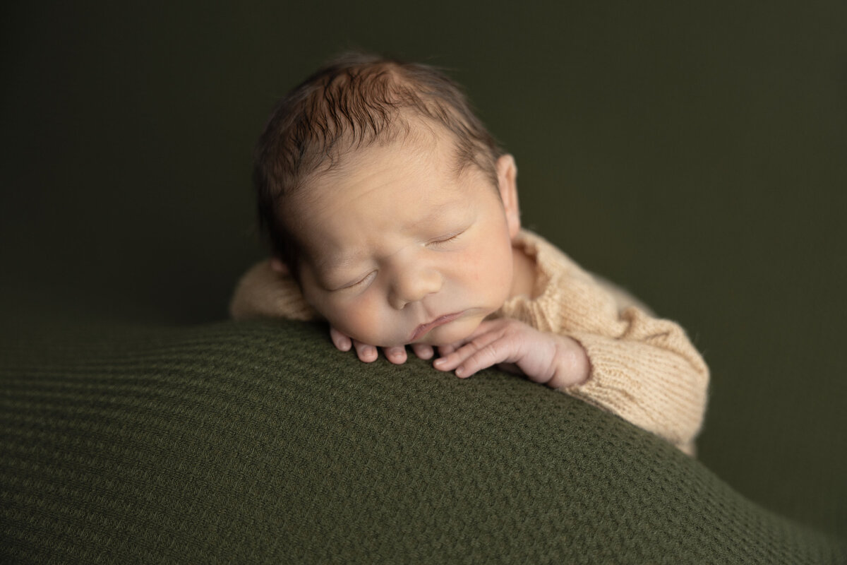 A baby rests his head on his hands to catch some sleep.
