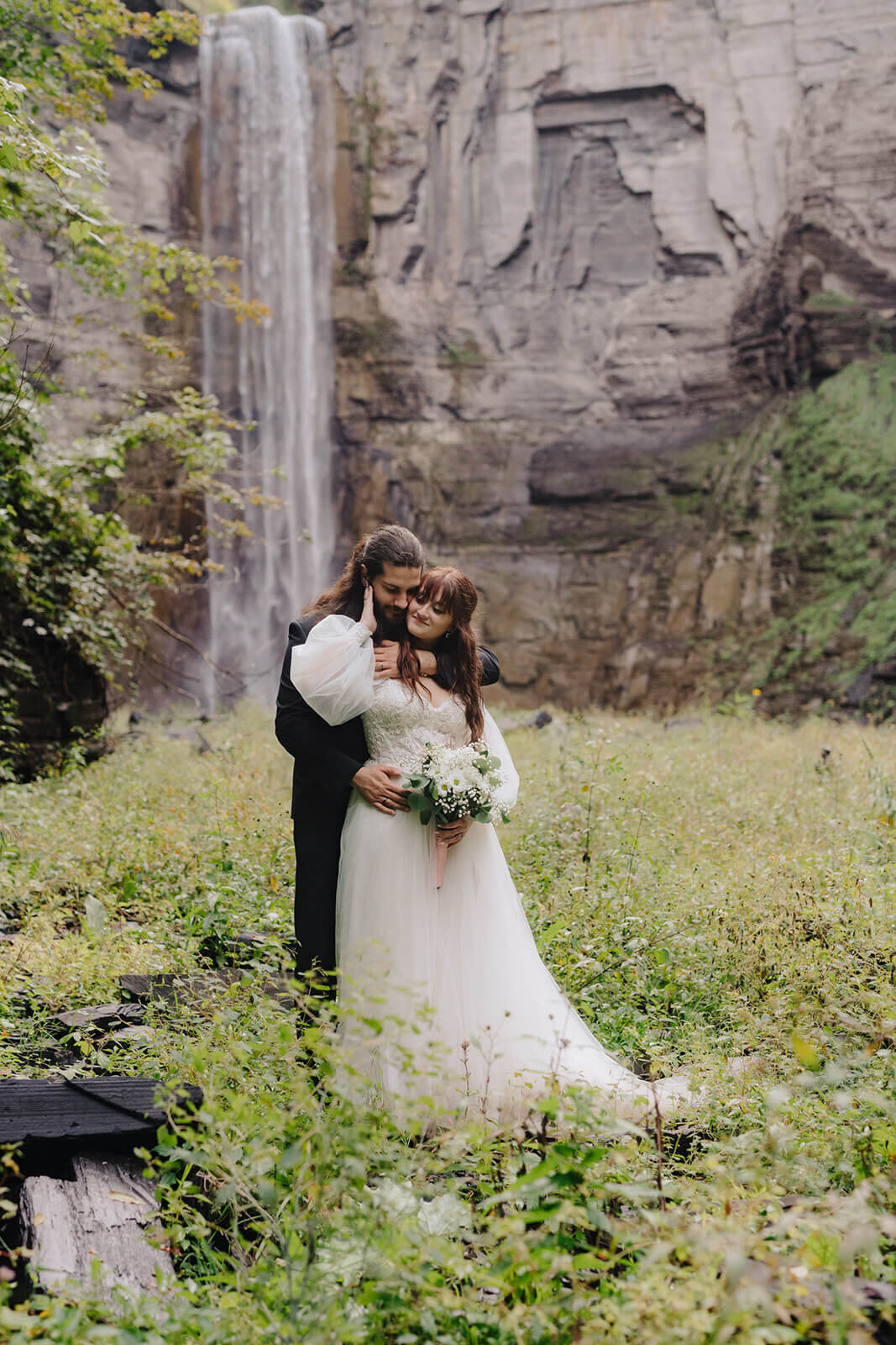 Bride and groom standing in front of waterfall at Finger Lakes wedding, NY
