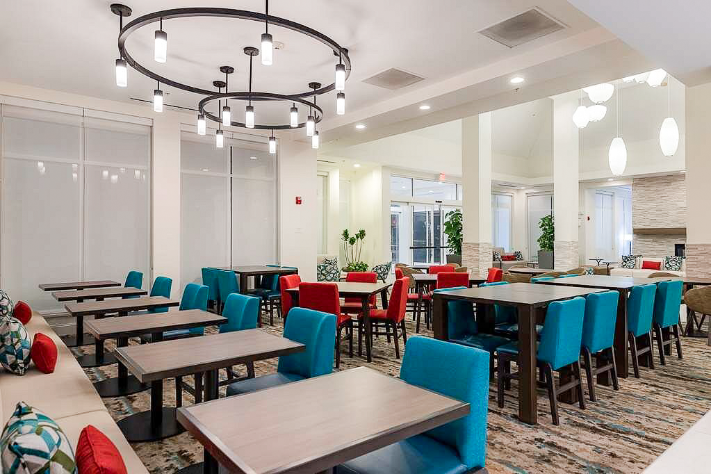 Modern hotel dining area with turquoise and red chairs