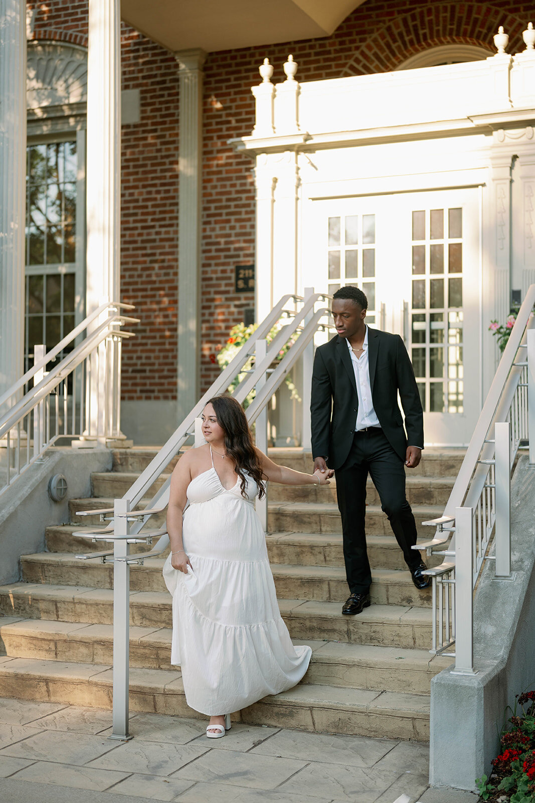 Couple walking down historic building steps during their downtown Kalamazoo engagement photos.