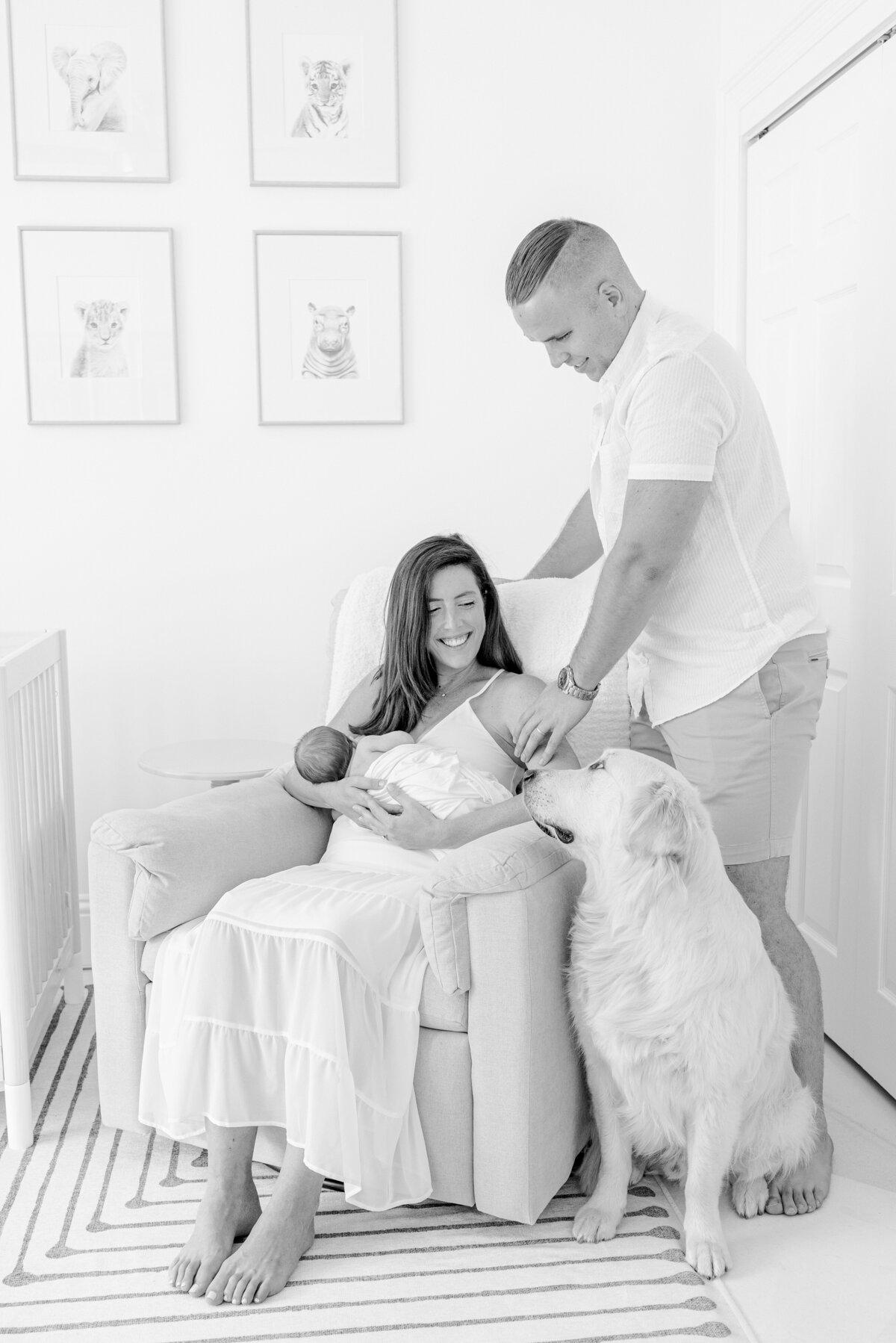 Family with dog holding newborn in nursery