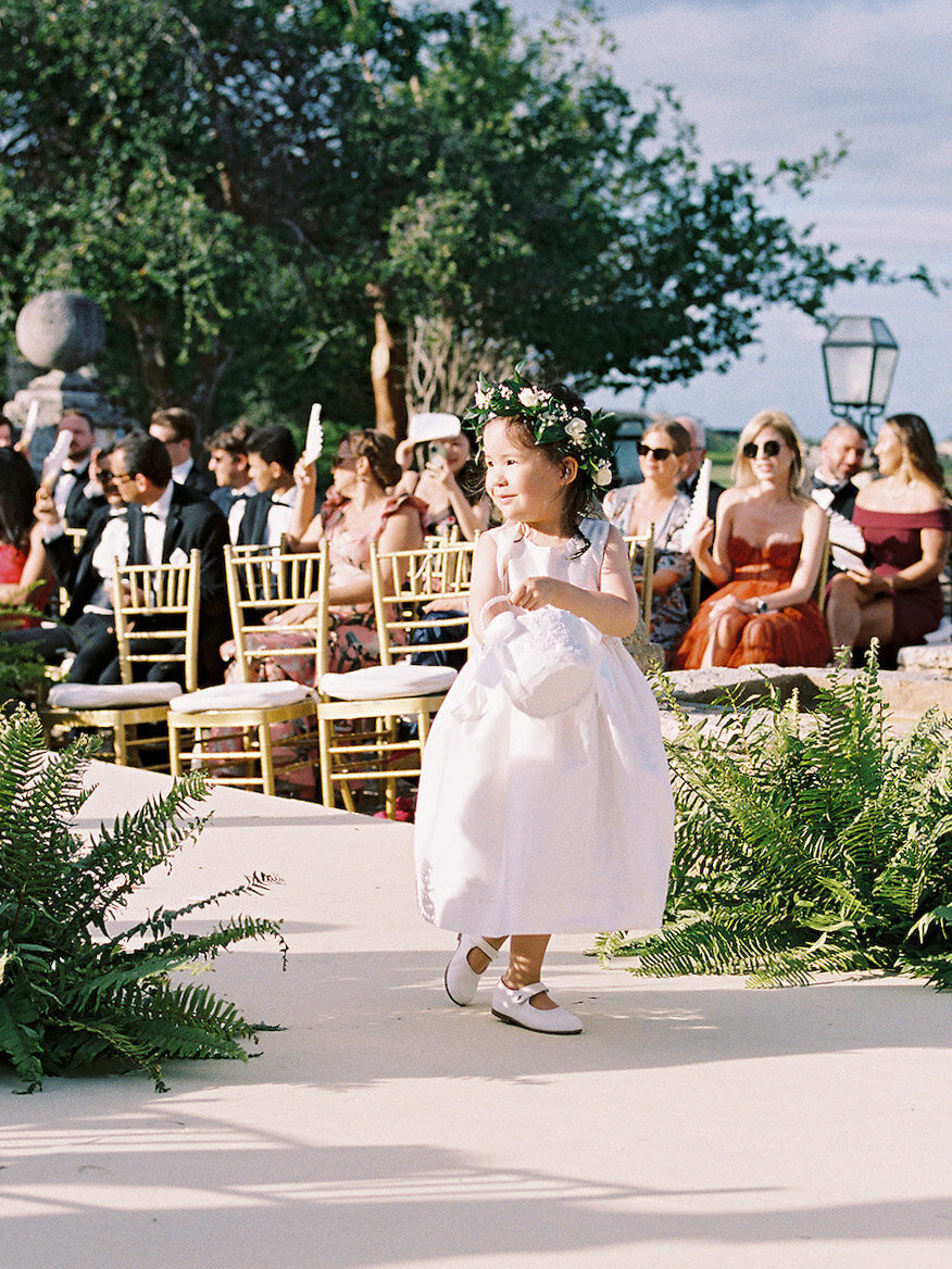 Flower girl wearing baby pink walking down the aisle at a destination wedding