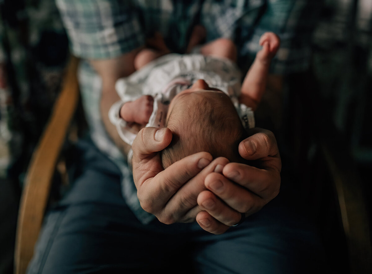 Newborn photography of a baby being held by dad.