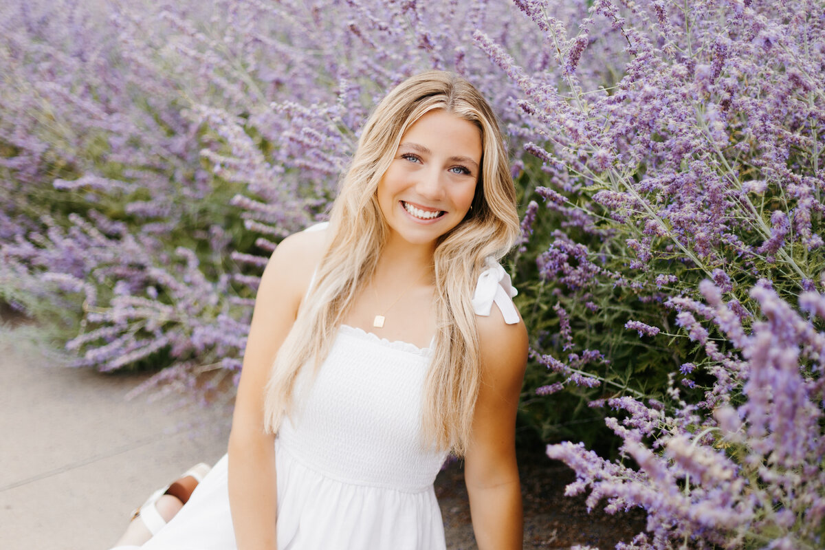 Girl in white dress sitting in front of lavender bushes