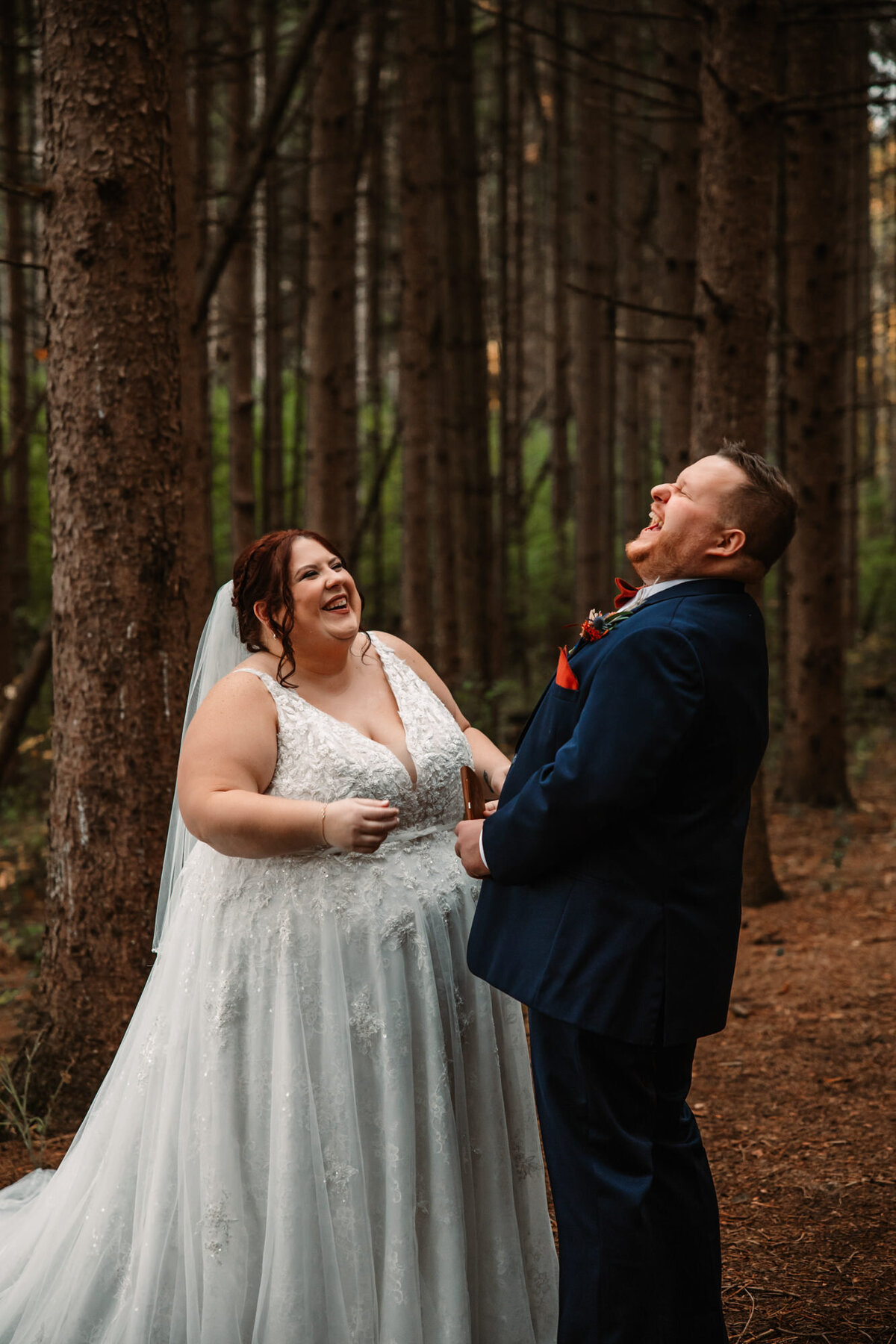 bride and groom laugh in forest