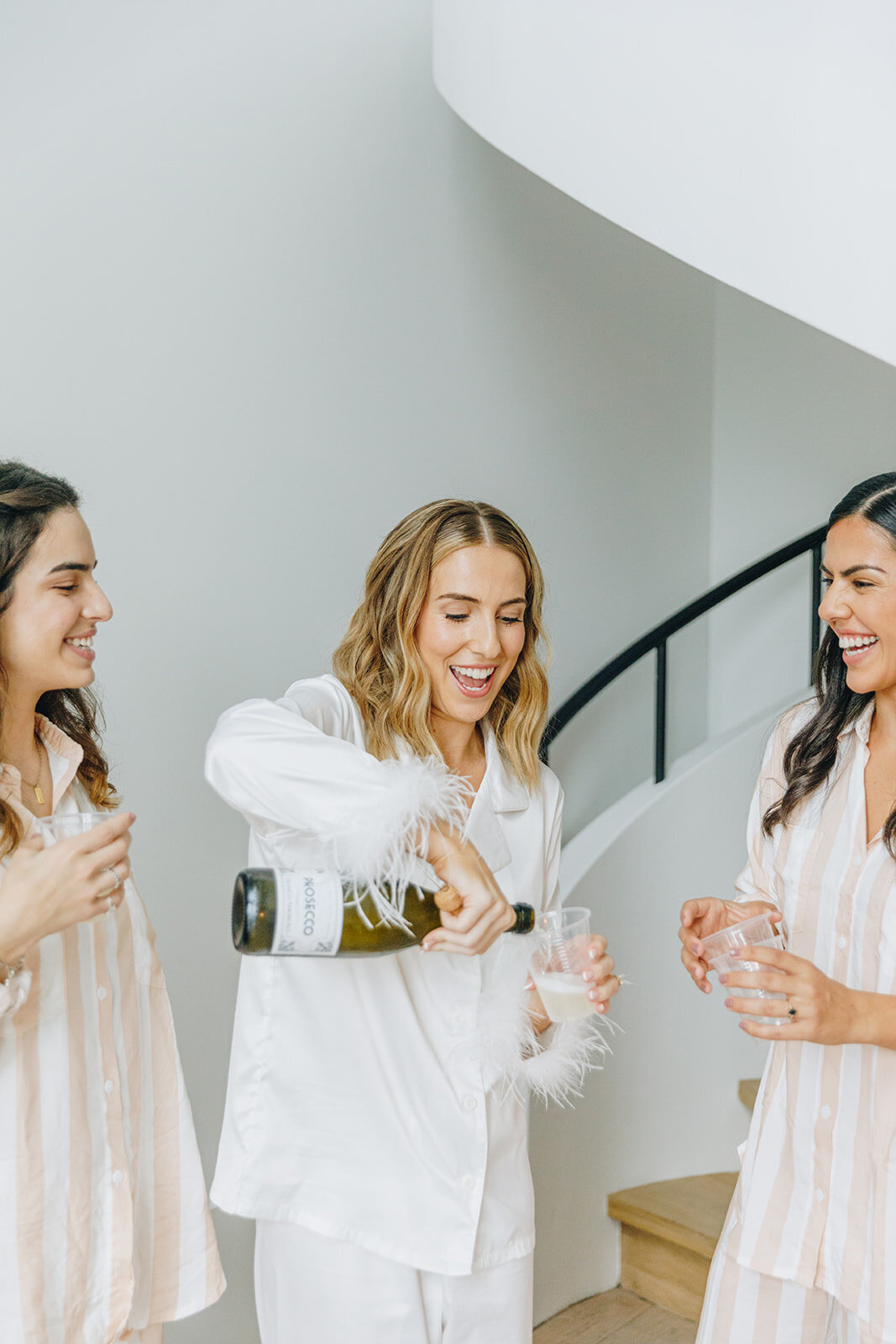 Bride pouring champange with her bridesmaids at indigo hotel