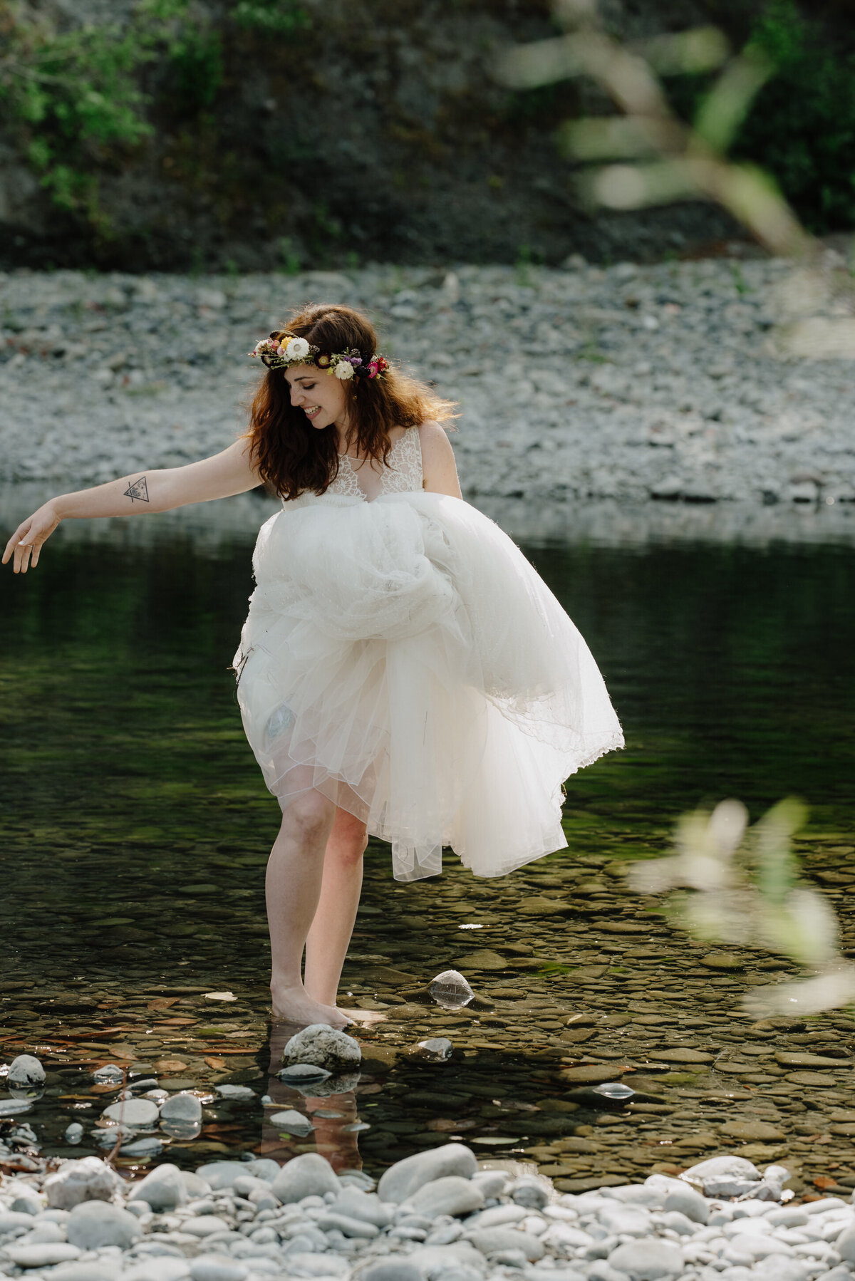 Bride reaches for groom while wading in the Van Duzen River