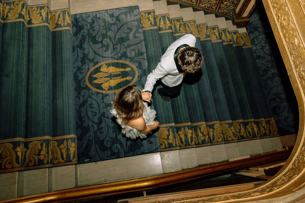 A newlywed couple walking down a staircase.