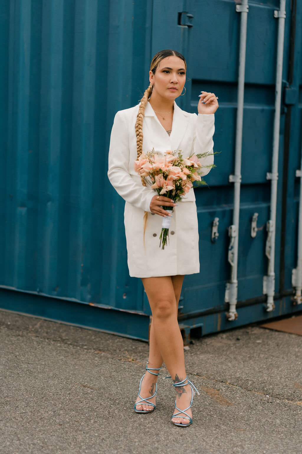 bride posing with one hand up towards her face and a bouquet in the other