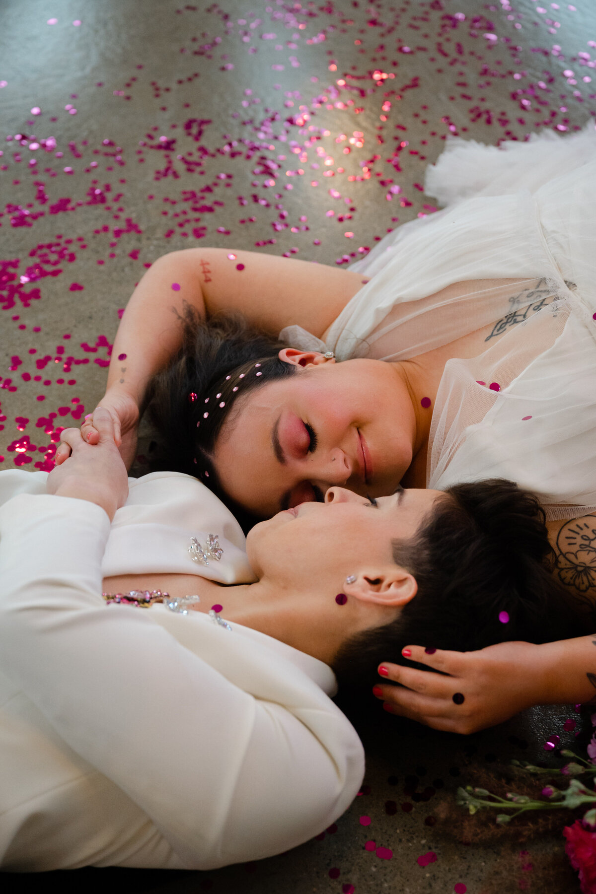 Brides laying on floor with pink confetti on ground
