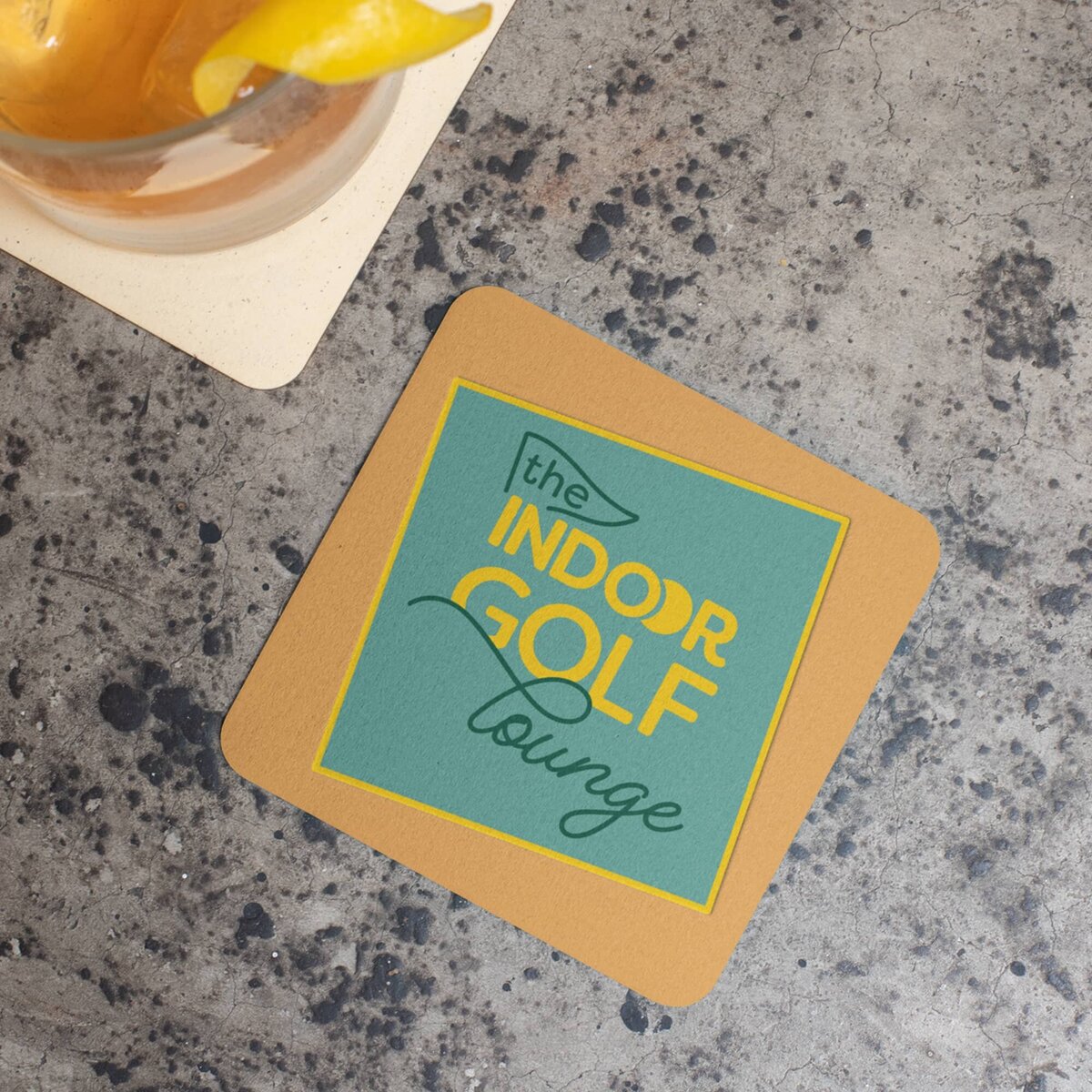 An square coster with rounded edges, printed in orange with The Indoor Golf Lounge logo in the middle