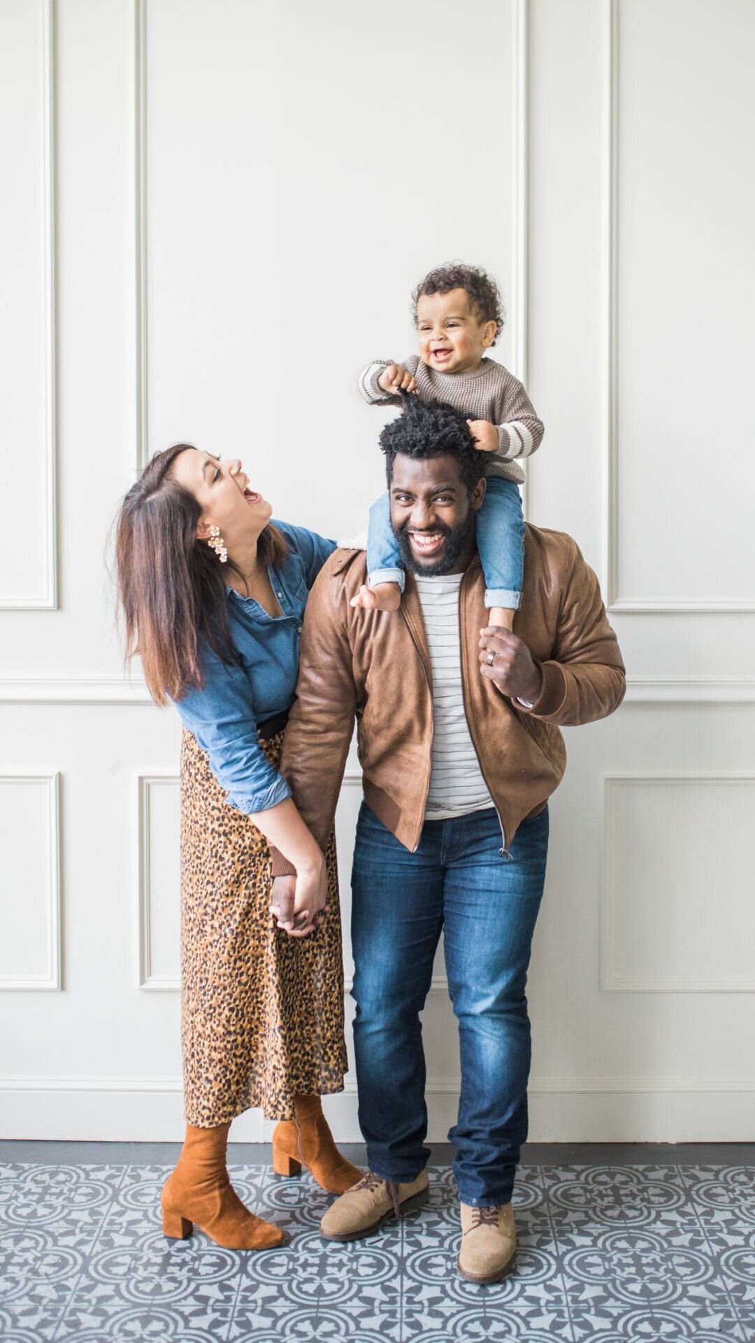 Family laughing together with toddler on father's shoulders