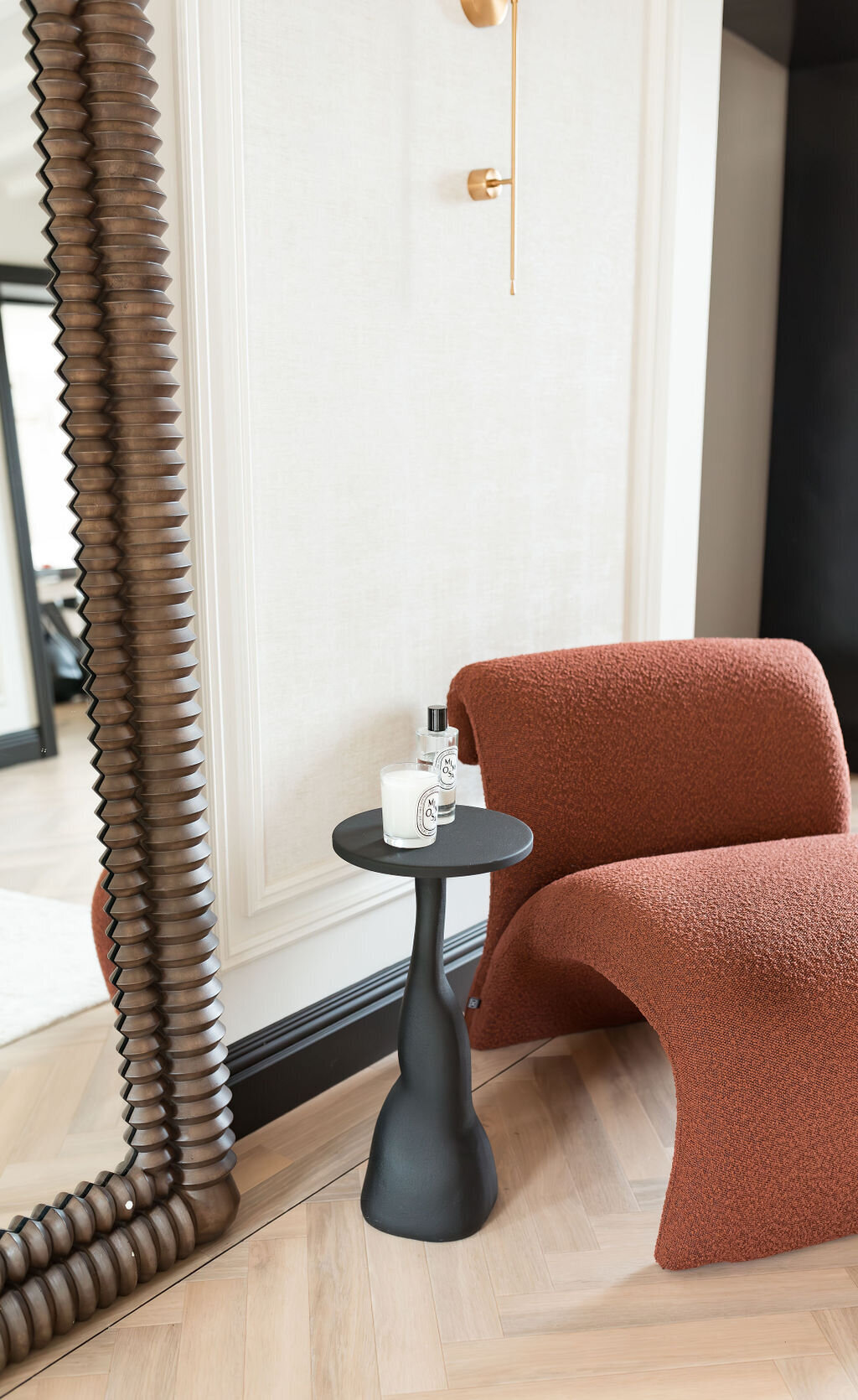 Small black side table next to a red chair in a modern foyer.