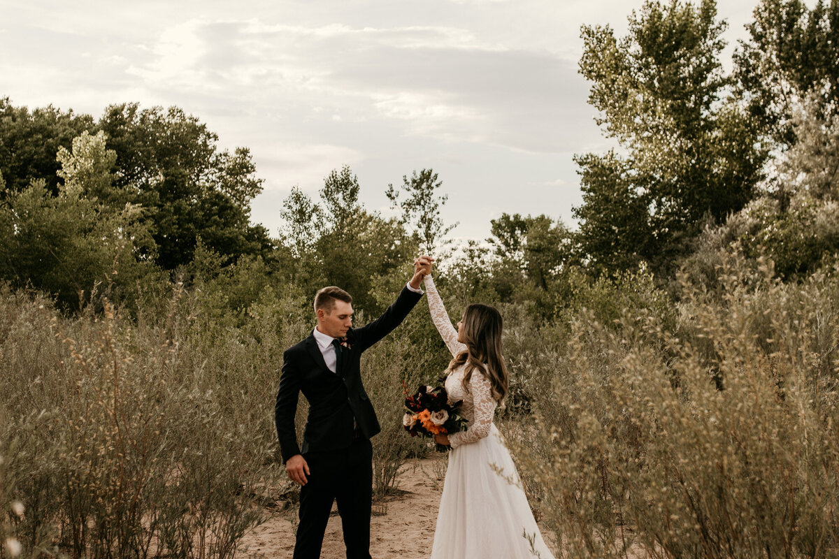 groom spinning bride with bouquet outdoors