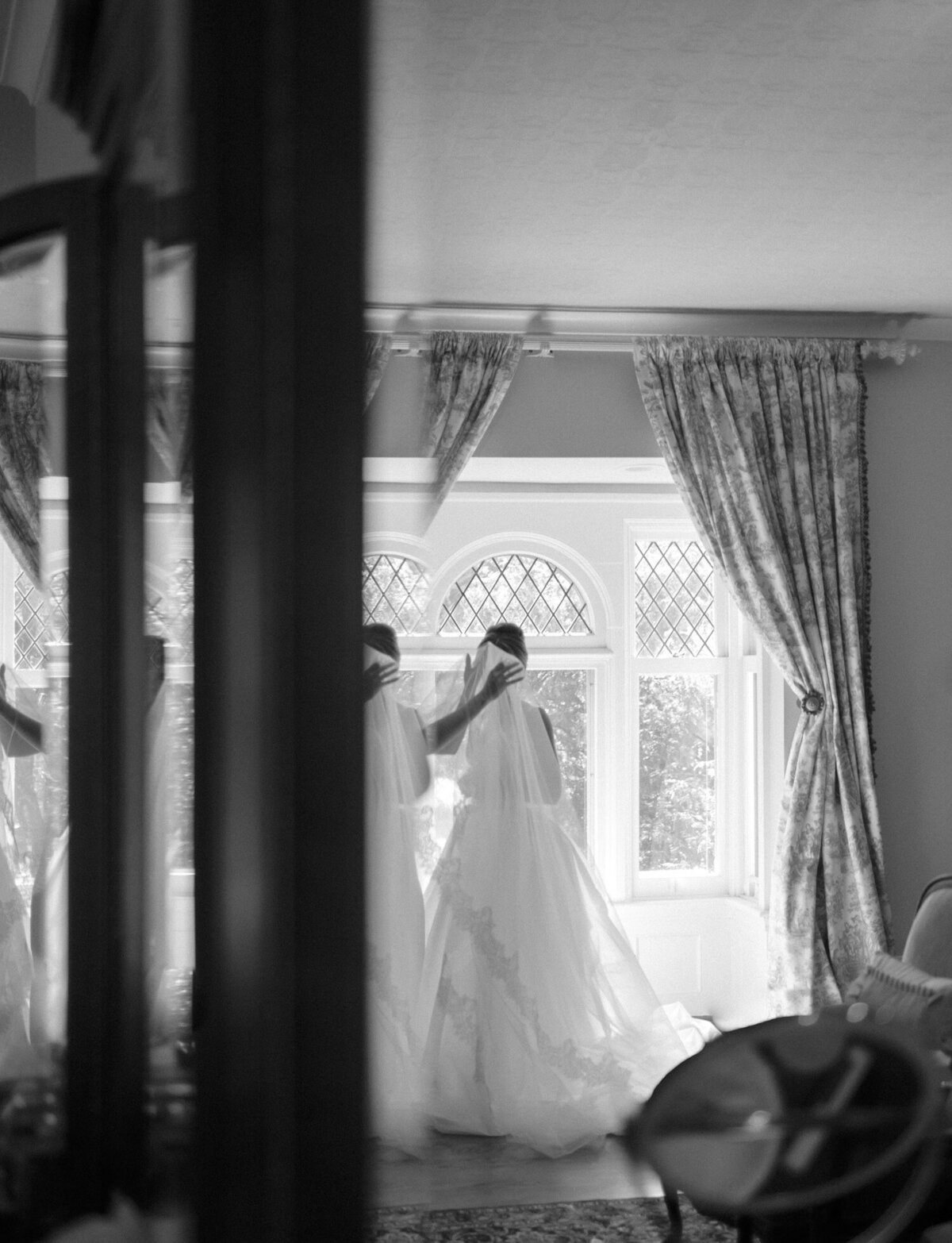 creative film wedding photography shows a bride having her veil placed, reflected in a mirror