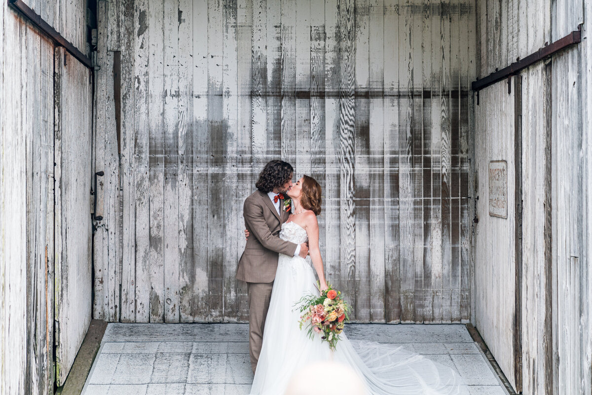 A beautiful wedding portrait of a bride and groom in front of the stunning barn doors at the North Coast Hitching Post in Loleta, CA, capturing the perfect blend of rustic charm and romance.
