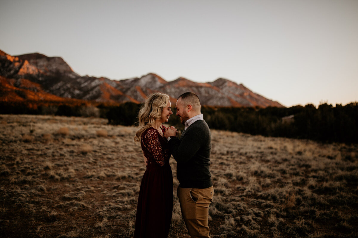 engaged couple holding hands with Sandia mountain behind them