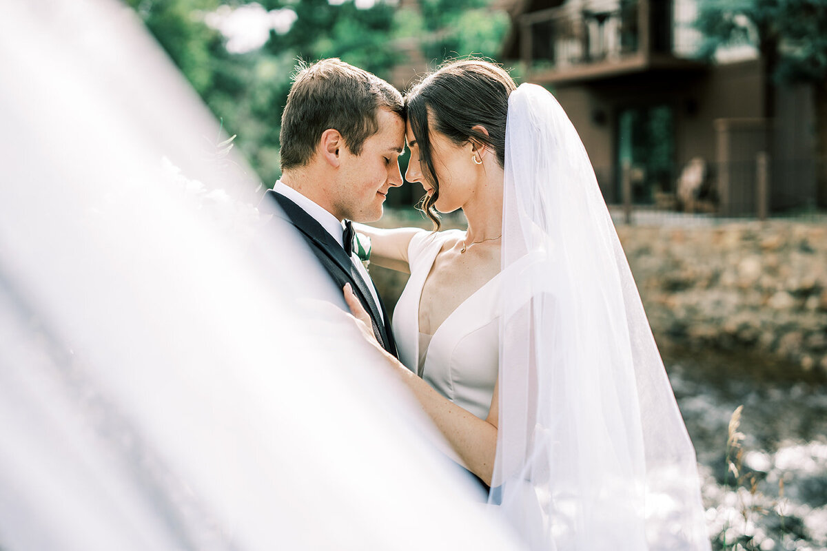 Bride and groom pose with her long white veil at their wedding venue, The Landing at Estes Park.