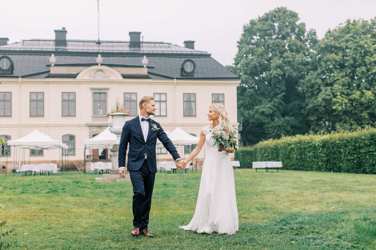 Bröllopspar håller varandras händer på en gräsmatta