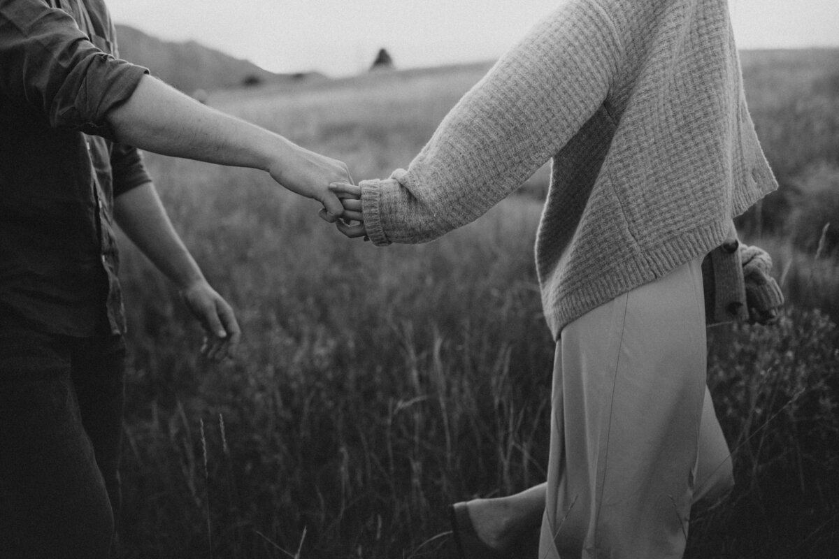 Engaged couple holding hands in a field in Boulder, CO