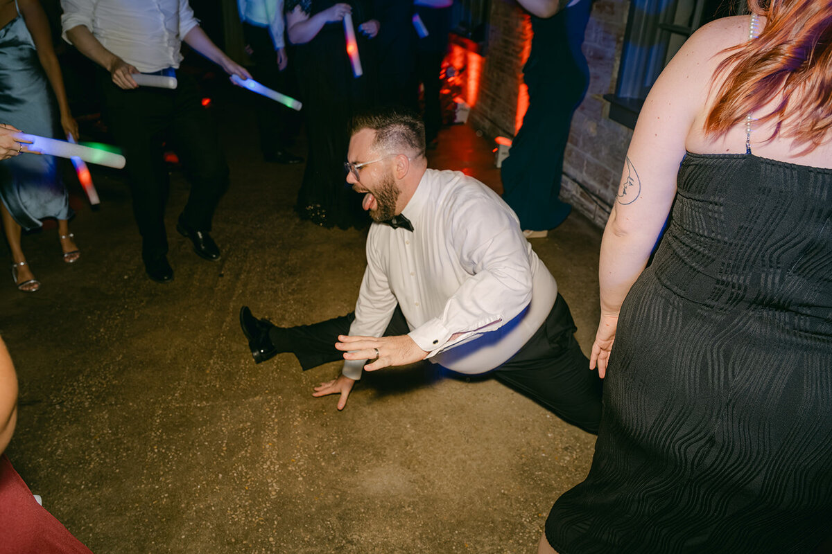Candid flash photography of energetic wedding guests dancing under saturated party lighting