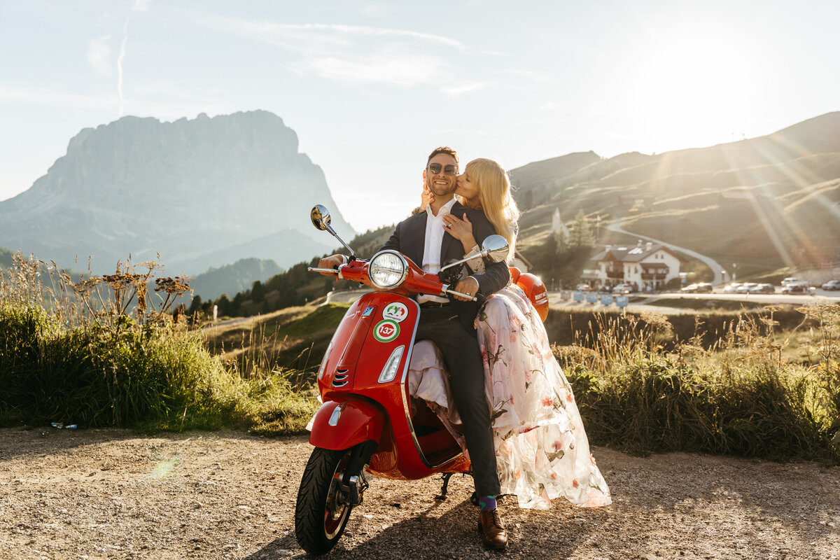 Couple riding Vespa at Passo Gardena during golden hour