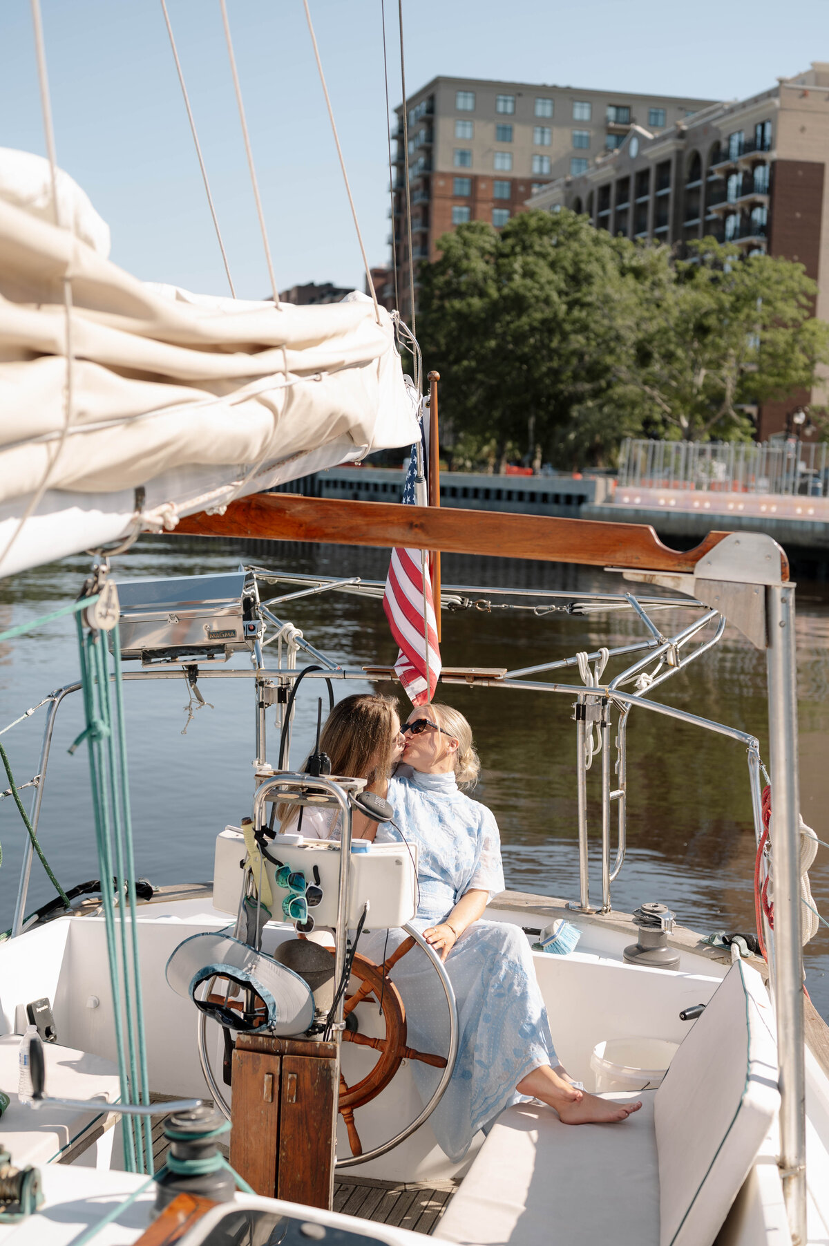 A bride and groom lean over a champagne tower, both sipping from green glassware.