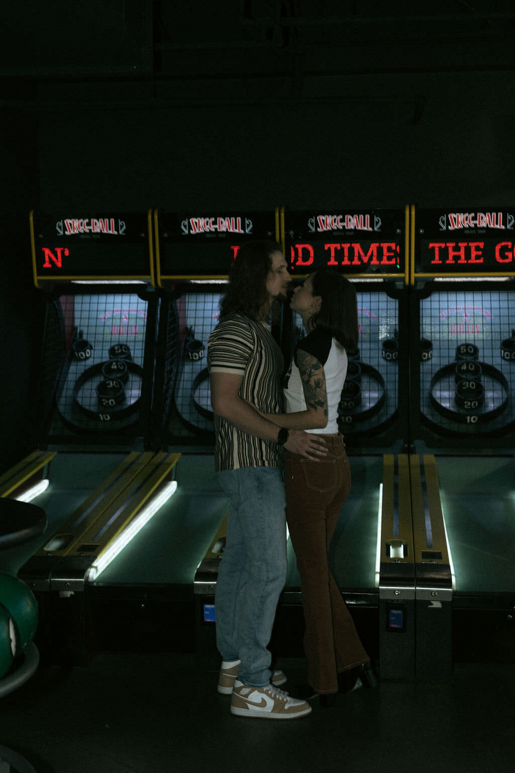 A couple about to kiss in front of pinball machines.