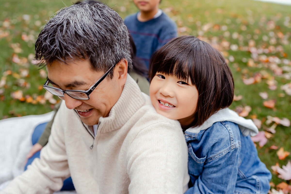 Sweet moment of a young boy smiling beside his father at O.O. Denny Park in Kirkland, WA, surrounded by peaceful nature.