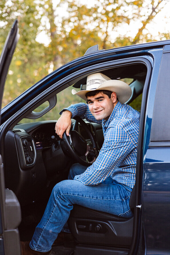 Boy with cowboy hat on sits in truck for his senior session with Angela Marie Media.