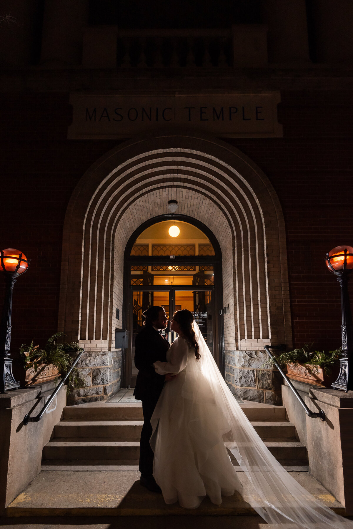 Silhouette-of-bride-and-groom-standing-outside-the-Asheville-Masonic-Temple-at-night-by-Charlotte-wedding-photographers-DeLong-Photography