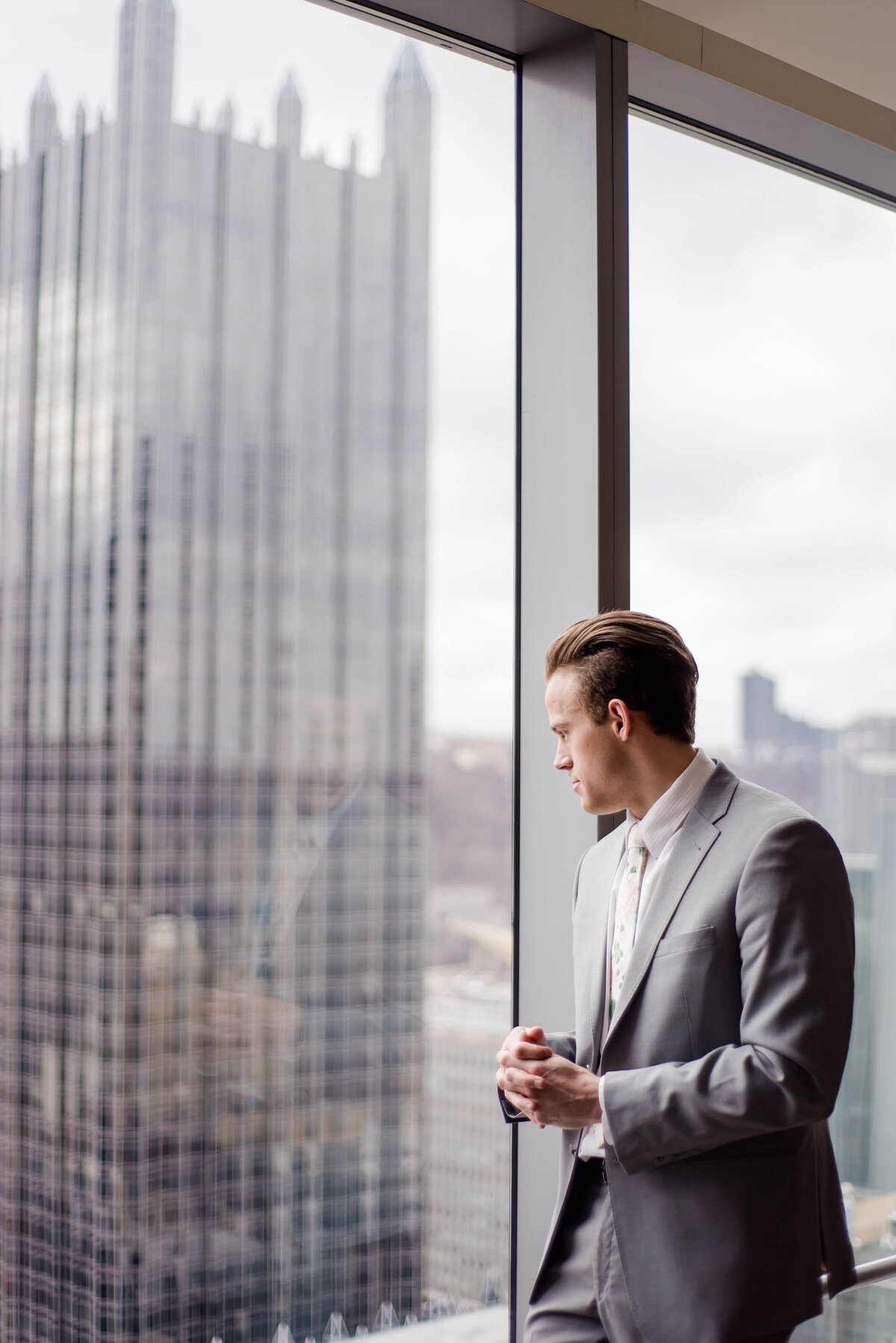 groom looking at the pittsburgh skyline from his hotel room at the fairmont hotel