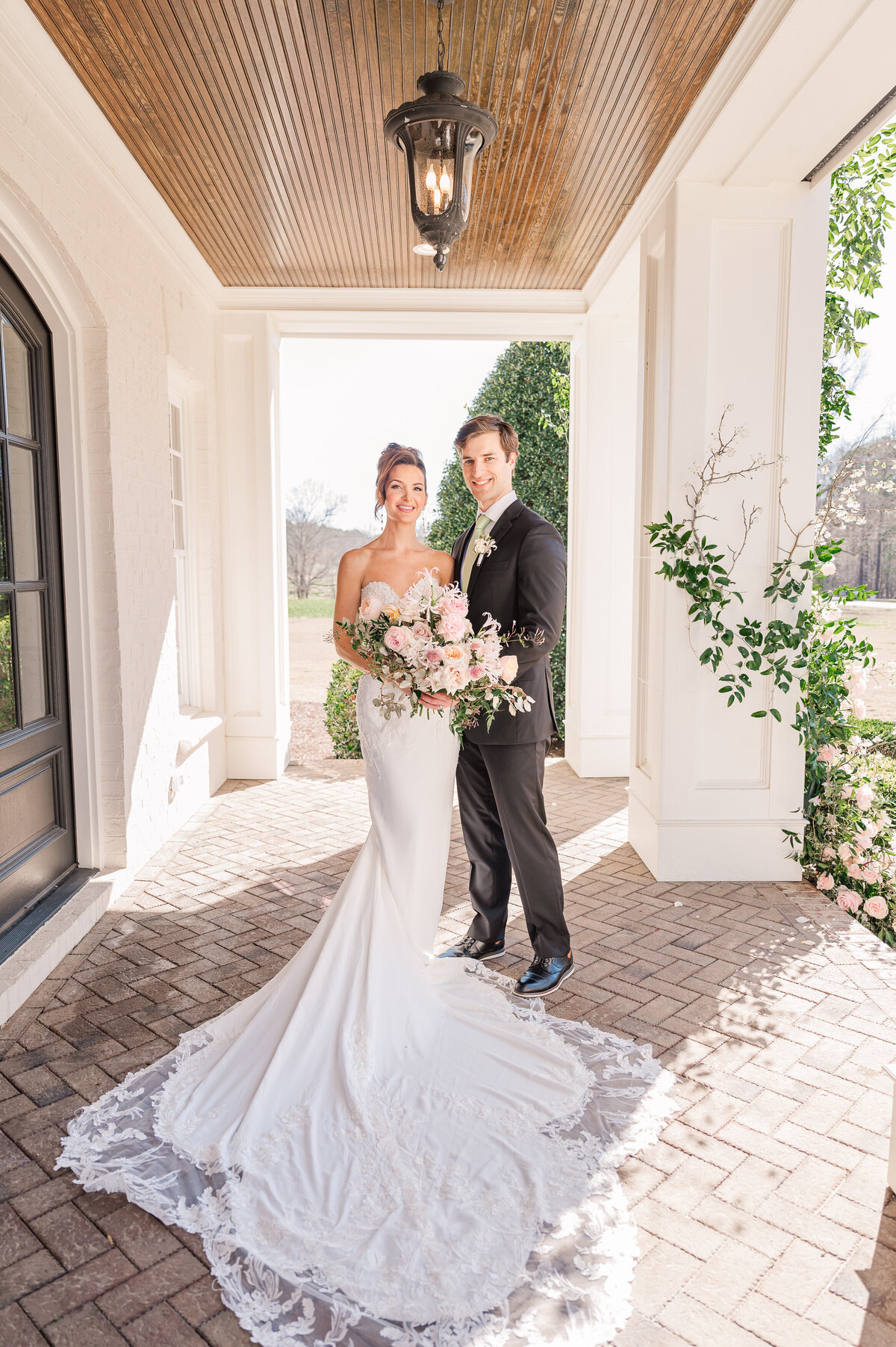 A gorgeous couple on their wedding day at Donovan Manor in the springtime on a stunning wrap around porch as they enjoy their Raleigh wedding photography session with JoLynn Photography