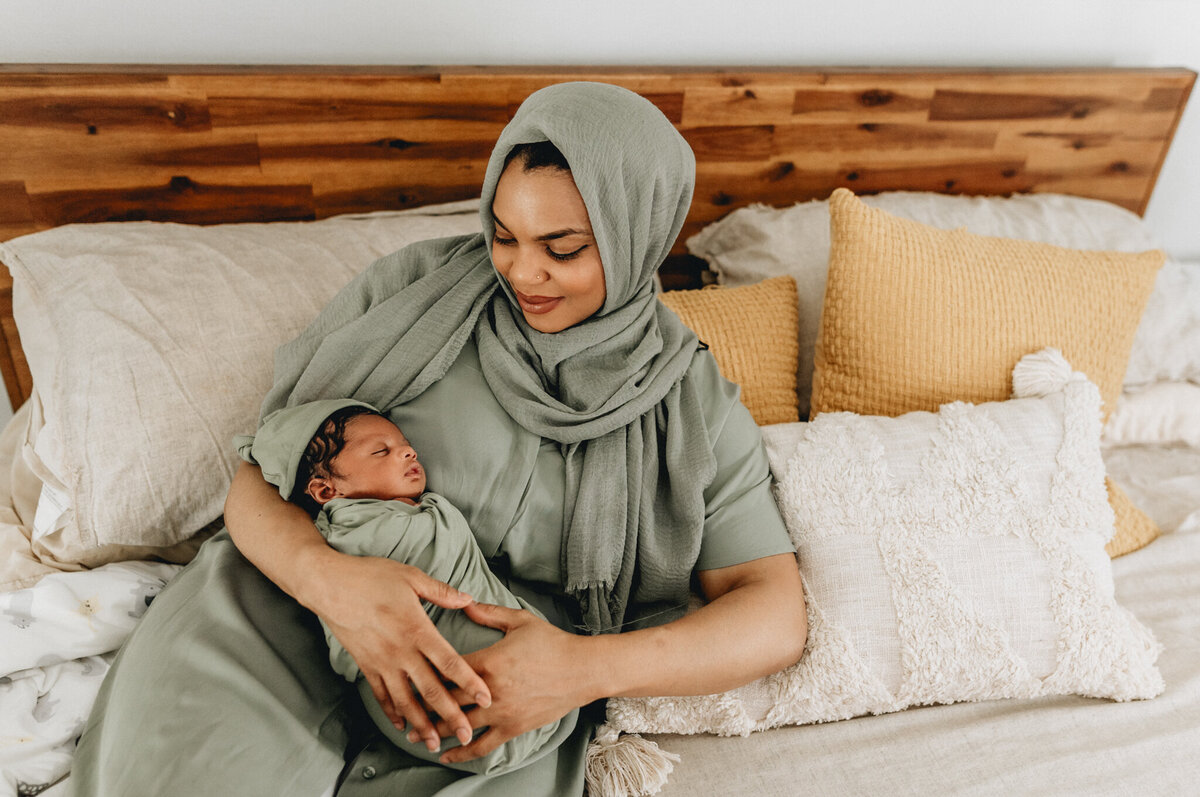 Newborn photography of mother holding newborn babe in bed.