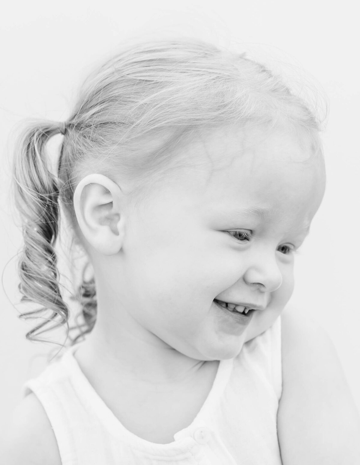 Toddler girl looking curious, bright white backdrop and simple composition