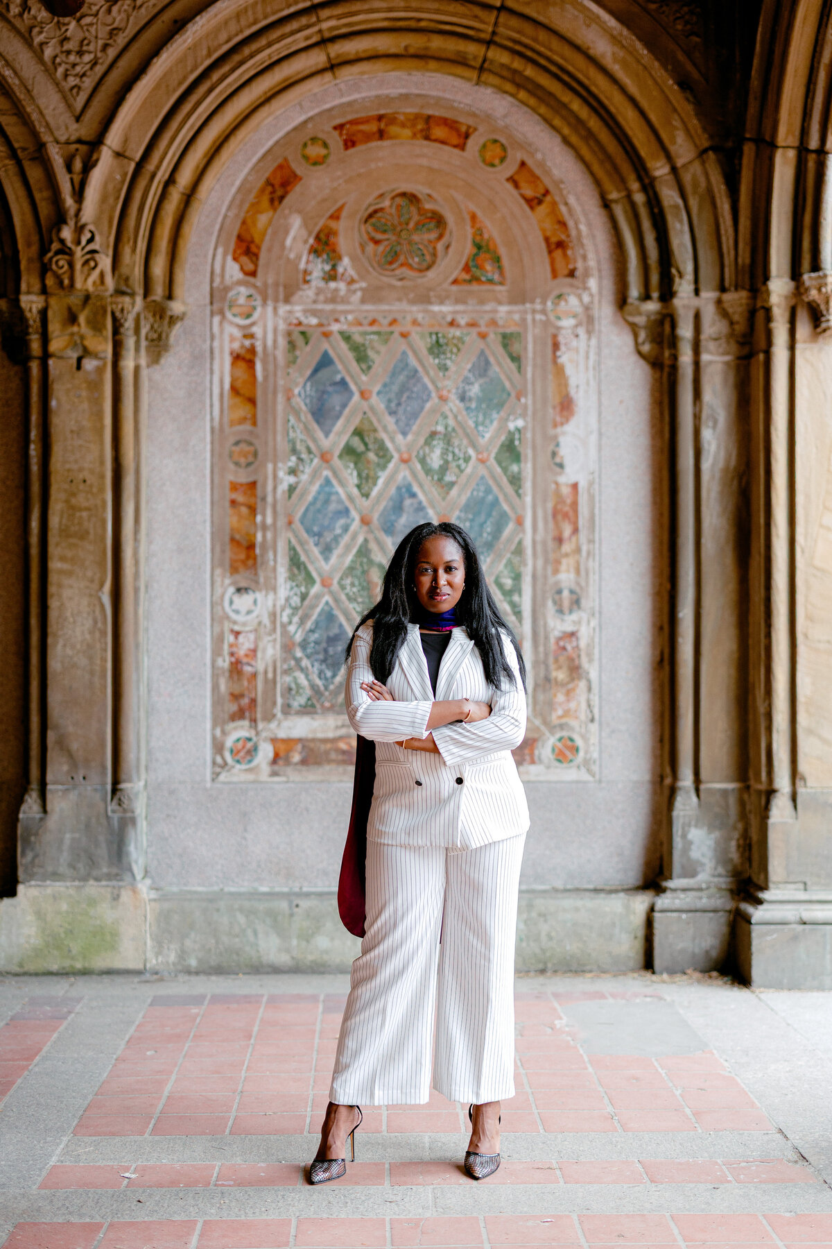 Fordham Law graduate standing confidently in white suit at Central Park.