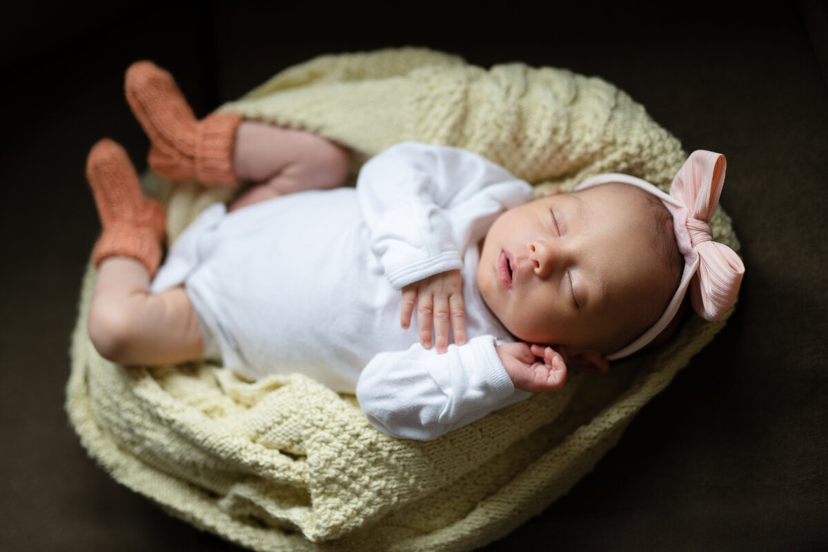 Close up of a baby in a basket with a yellow blanket.