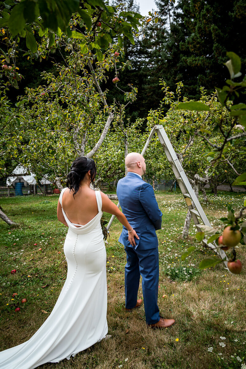 A fun and lighthearted moment as the bride playfully touches the groom’s butt before he turns around for their first look at Mitchell Grove in Eureka, CA, capturing their joyful personalities.