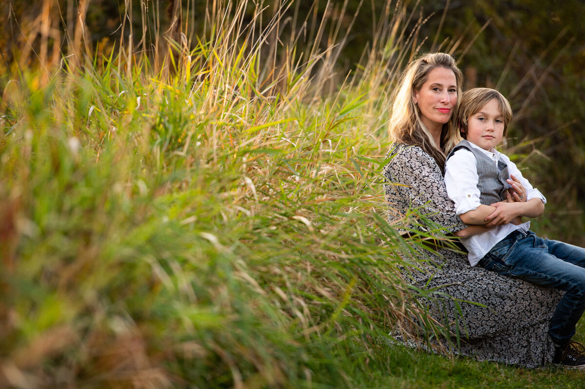Ottawa family photography of a mom and her son sitting in a grassy field at sunset golden hour
