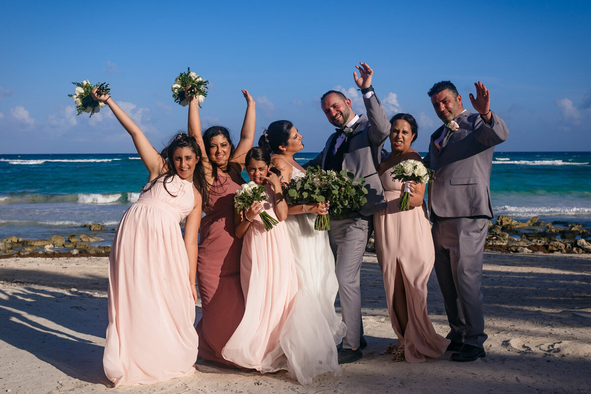 Bride and groom with their families holding floral bouquets on the seaside