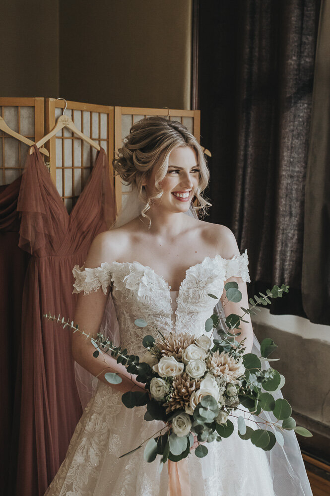 bride smiling and holding a flower bouquet