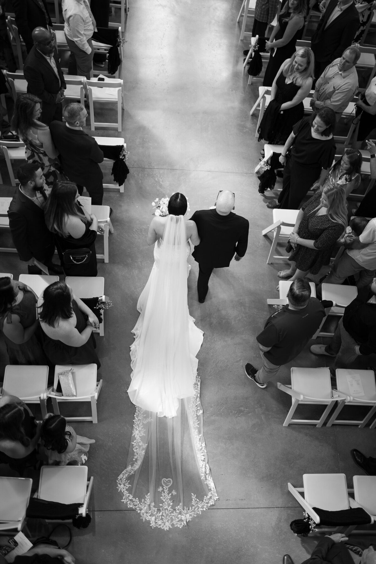 Bride walking down aisle with father in chapel