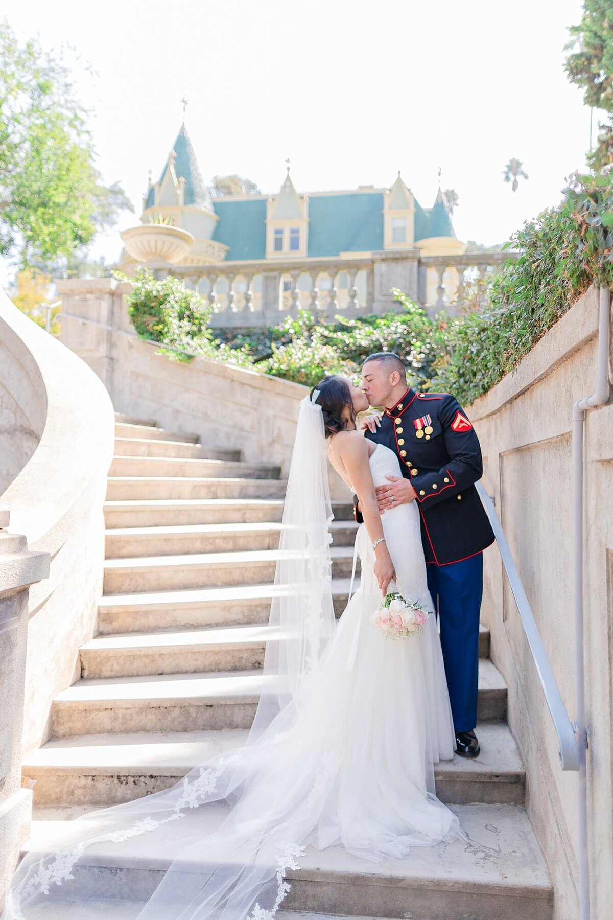 bride and groom kiss on a staircase of a fairytale castle