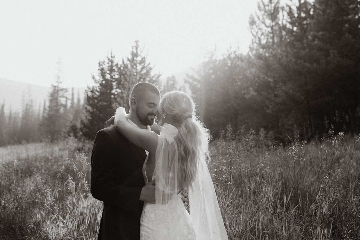 Black and white photo of bride and groom embracing in mountains