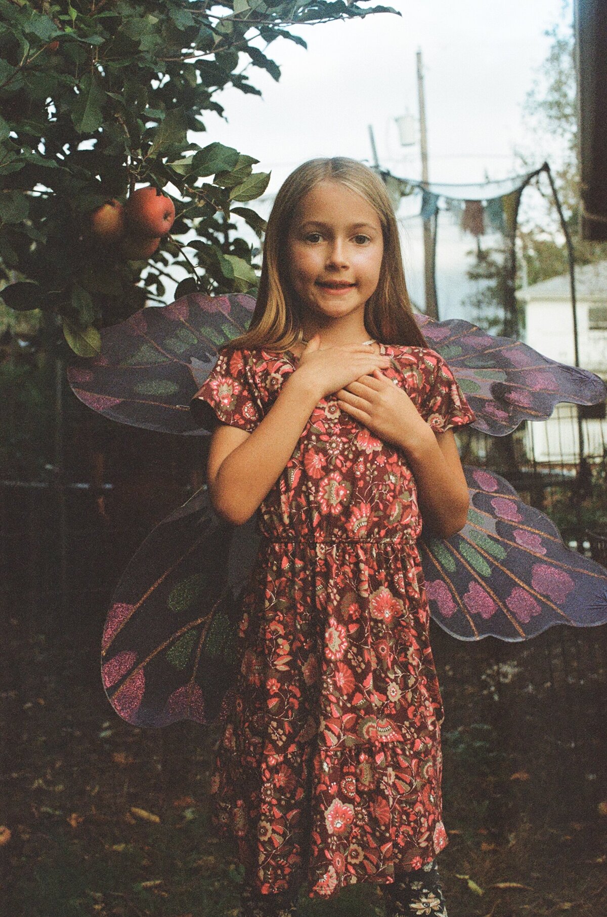 Portrait of a child wearing butterfly wings standing outside